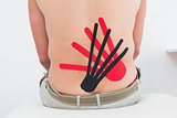 Shirtless man with red and black kinesio tapes on back