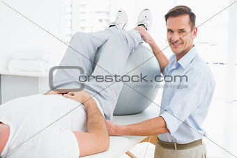 Physical therapist assisting man with yoga ball