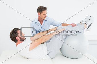 Physical therapist assisting young man do sit ups