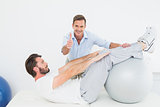 Therapist gestures thumbs up while assisting man do sit ups