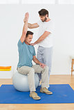 Man on yoga ball working with a physical therapist