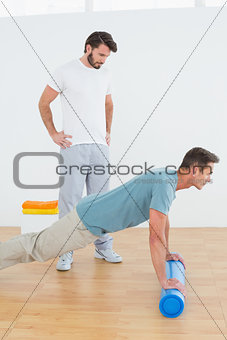 Physical therapist watching young man do push ups