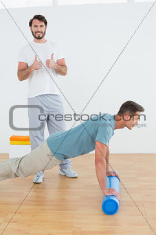 Therapist gesturing thumbs up with man doing push ups