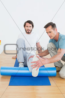 Physical therapist examining young man's leg