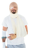Young man with head tied up in bandage and broken hand