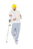 Man in hard hat with broken hand and crutch
