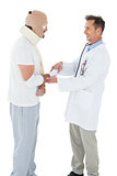Doctor shaking hands with patient tied up in bandage