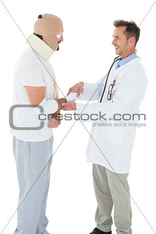 Doctor shaking hands with patient tied up in bandage
