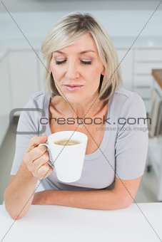 Casual young woman drinking coffee in kitchen