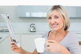 Smiling woman with coffee cup and newspaper in kitchen