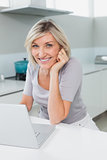 Casual happy woman with laptop in kitchen