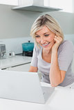 Casual happy woman using laptop in kitchen