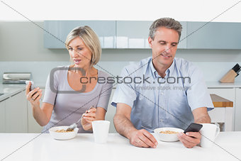 Couple reading text messages while having breakfast