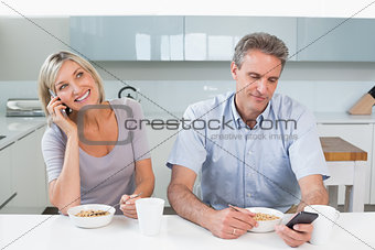 Couple with cellphones while having breakfast