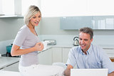 Couple with coffee cup and laptop in kitchen