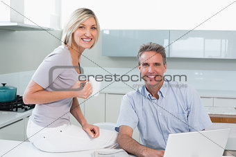 Couple with coffee cup and laptop in kitchen