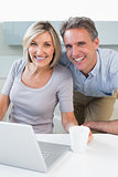 Happy casual couple using laptop in kitchen