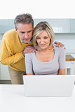 Couple looking at laptop in kitchen