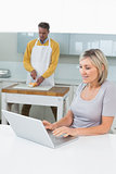 Woman with laptop and man chopping vegetables
