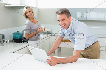 Happy man and woman with laptop in the kitchen