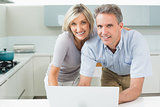 Portrait of a happy couple with laptop in kitchen