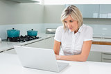 Casual young woman using laptop in kitchen