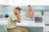 Man covering his ears as woman argue in kitchen