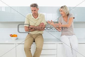Man with arms crossed as woman argue in kitchen