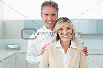 Man standing behind a happy woman in kitchen