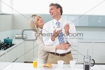 Woman embracing a happy man from behind in kitchen