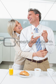 Woman embracing a happy man from behind in kitchen