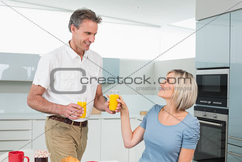 Happy couple with orange juices in kitchen