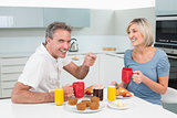 Happy couple having breakfast in kitchen