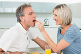 Loving woman feeding man in the kitchen