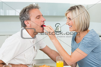 Loving woman feeding man in the kitchen