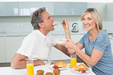 Woman feeding man at breakfast table in kitchen