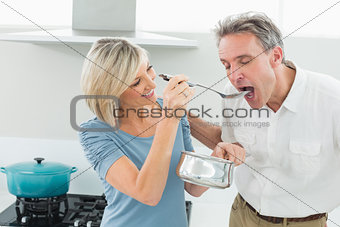 Loving woman feeding a man in kitchen