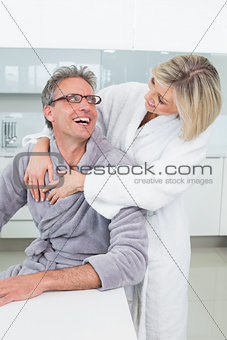 Woman embracing a man from behind in kitchen
