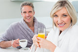 Happy couple in bathrobes having breakfast