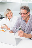 Couple in bathrobes using laptop in kitchen