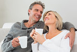 Relaxed happy couple with coffee cups in living room