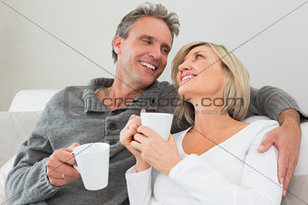 Relaxed happy couple with coffee cups in living room
