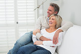Happy couple embracing while sitting on sofa