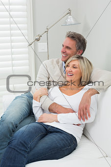 Happy loving couple embracing on sofa at home