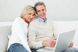 Happy casual couple using laptop at home