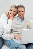 Happy casual couple using laptop at home