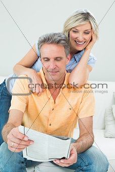 Happy couple reading newspaper in living room