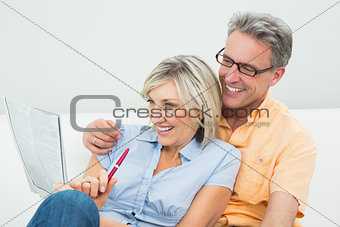Happy couple doing the newspaper crossword puzzle at home