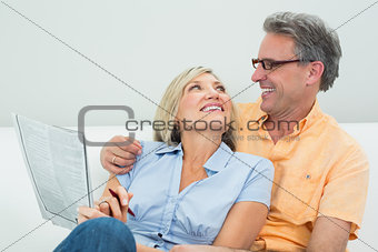 Happy couple with newspaper in the living room