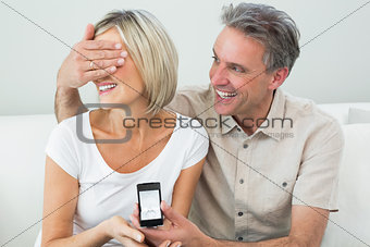 Man covering woman's eyes to offer her an engagement ring